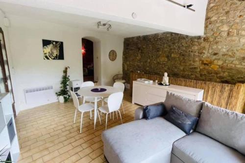 una sala de estar con un sofá y una mesa en Gîte des 3 vallées - Le soleil des Cévennes, en Saint-Jean-du-Gard