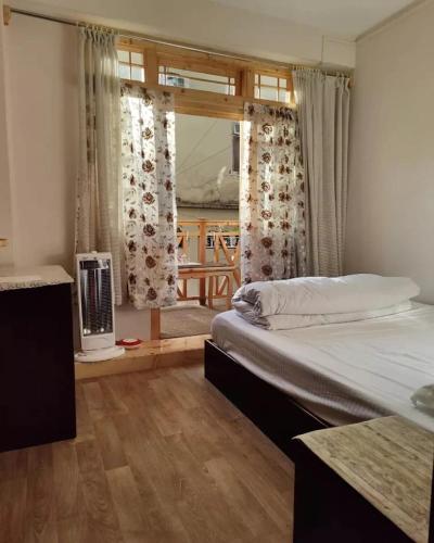 - une chambre avec un lit, une fenêtre et une table dans l'établissement BaalaChhen Urban Home Stay, à Gangtok