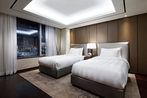 a bedroom with two beds and a window at LOTTE City Hotel Ulsan in Ulsan