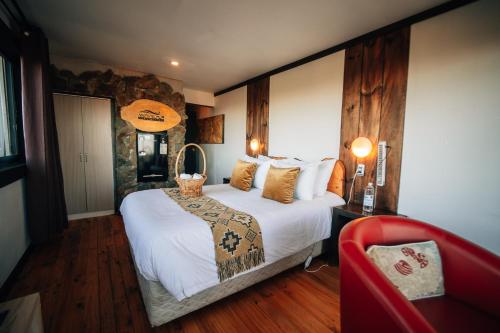 a bedroom with a large bed and a red chair at Moana Pichilemu Lodge in Pichilemu