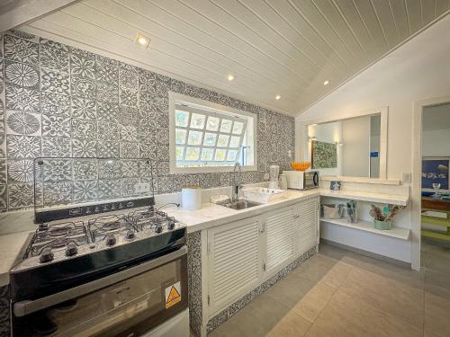 uma cozinha com um fogão e um lavatório em BZ61 Casa com Piscina a 50m da Praia da Ferradura em Búzios