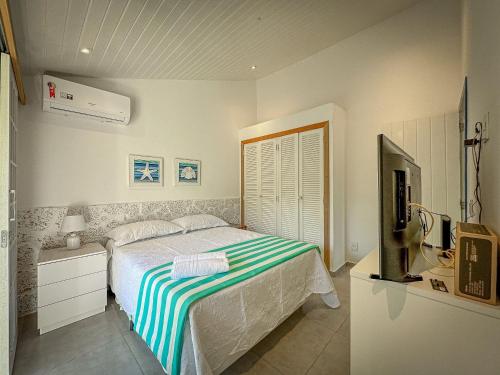 um quarto com uma cama e uma televisão em BZ61 Casa com Piscina a 50m da Praia da Ferradura em Búzios
