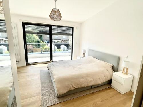 a white bedroom with a bed and a large window at Modern townhouse with Private Garden in Differdange