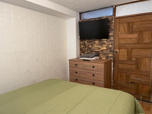 um quarto com uma cama e uma televisão na parede em Casita acogedora en cusco em Cusco