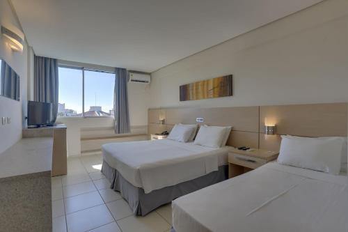 a hotel room with two beds and a television at Hotel Porto Sol Ingleses in Florianópolis