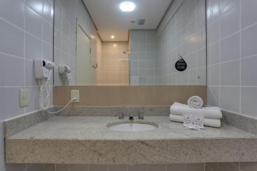 a bathroom with a sink with a phone and towels at Hotel Porto Sol Ingleses in Florianópolis