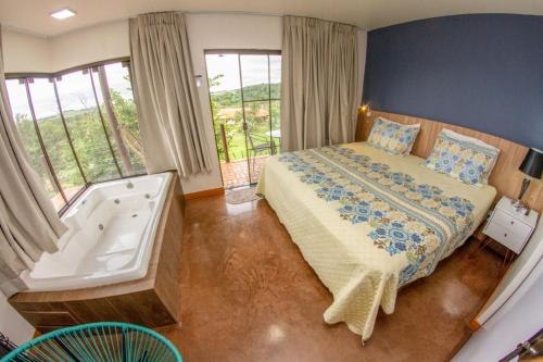 um quarto com uma cama e uma banheira ao lado de uma janela em Hotel Fazenda Vale Alvorada em Cascavel