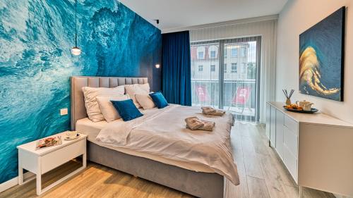 1 dormitorio con 1 cama grande y pared azul en Rezydencja Niechorze 208 z 2 sypialniami i 2 łazienkami przy Plaży - 5D Apartamenty en Niechorze