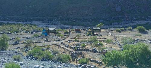 a group of huts on a hill with a mountain at Glamping Roots del Yeso in Los Chacayes