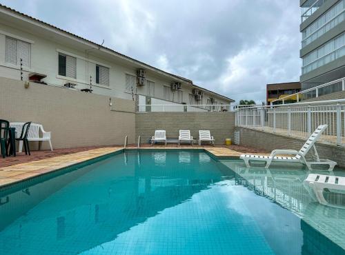 uma piscina com cadeiras e um edifício em Apto a 350m da Praia de Maitinga em Bertioga SP em Bertioga