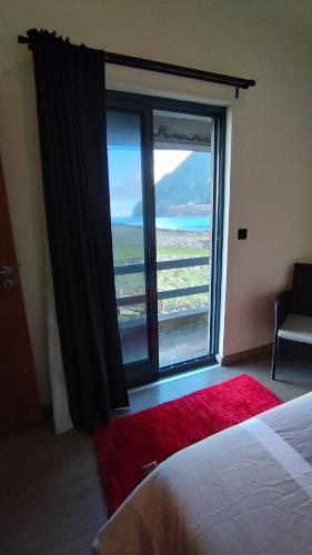 a bedroom with a large window with a view of the ocean at Cantinho da Fajã in Faja Grande
