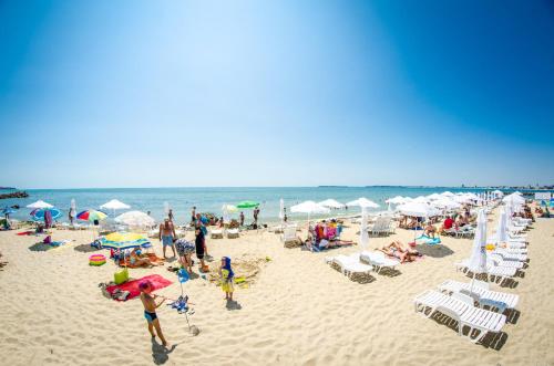 eine Menschenmenge an einem Strand mit Sonnenschirmen in der Unterkunft Premier Fort Beach Resort in Sonnenstrand