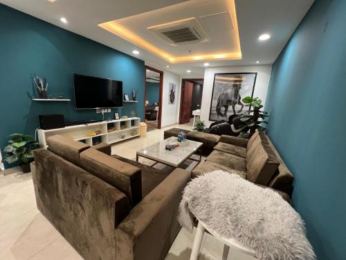 salon z brązową kanapą i niebieskimi ścianami w obiekcie 2BR Gold Crest Luxurious Residency Apartment BY AirHomes DHA Lahore w mieście Lahaur