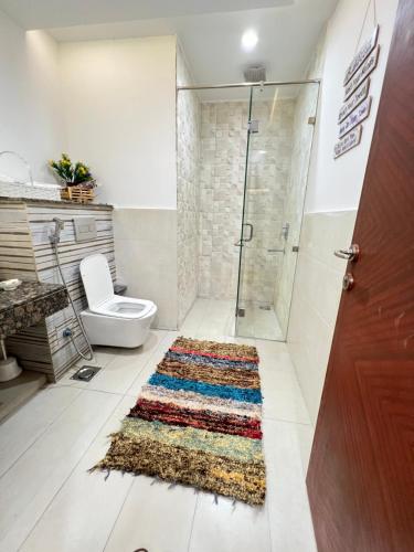 La salle de bains est pourvue d'une douche, de toilettes et d'un tapis. dans l'établissement 2BR Gold Crest Luxurious Residency Apartment BY AirHomes DHA Lahore, à Lahore