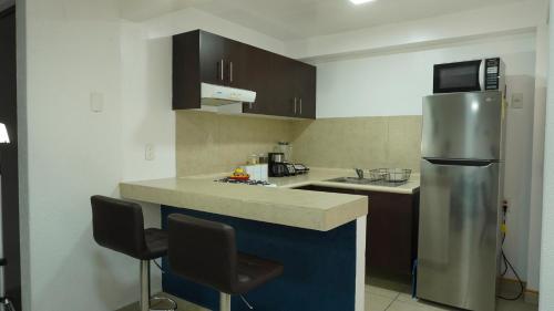 a kitchen with a stainless steel refrigerator and two chairs at Depa Balcones cerca Estadio GNP, Palacio de los Deportes, Autódromo HR y Aeropuerto CDMX in Mexico City