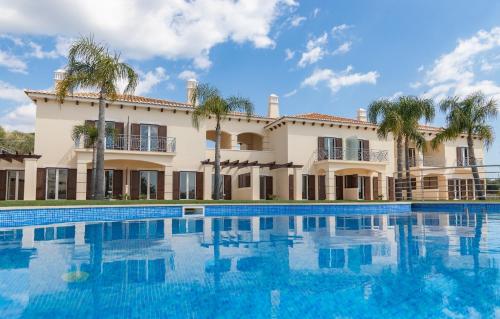 a building with a swimming pool and palm trees at Villa Cascata, 3 bedroom, Pool, close to Olhos de Agua in Albufeira