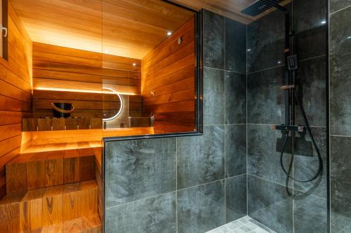 a bathroom with a shower with wooden walls at Nordic Apartment Katajaranta in Rovaniemi