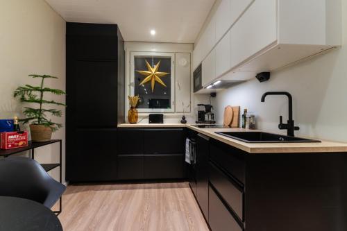 a kitchen with black cabinets and a sink and a window at Nordic Apartment Katajaranta in Rovaniemi