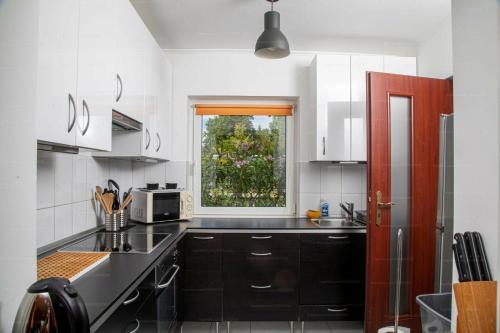 eine Küche mit schwarzen Arbeitsplatten und einem Fenster in der Unterkunft Sorompó Vendégház in Balatonkenese