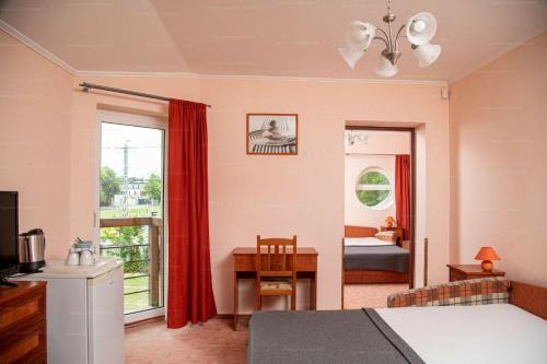 a bedroom with a bed and a desk and a window at Sorompó Vendégház in Balatonkenese