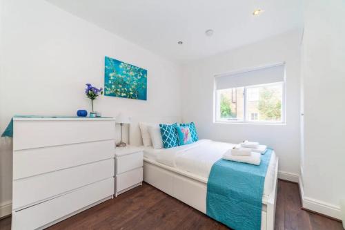 a white bedroom with a bed and a window at Radiant and Roomy 2BD Flat - Fulham! in London