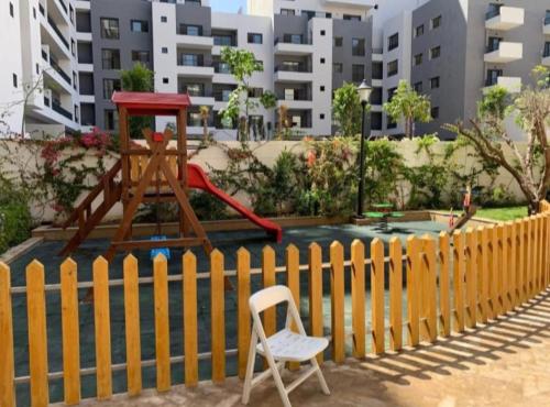 una silla sentada junto a una valla con parque infantil en Appartement Calme avec Piscine Mohemmadia Zenata, en Aïn Harrouda