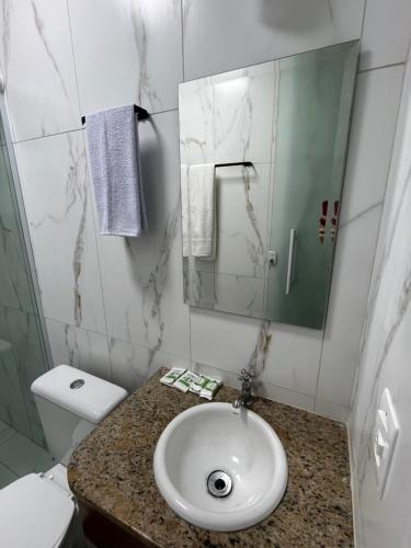 a bathroom with a sink and a toilet and a mirror at Pousada Dona Carmem Ubatuba in Ubatuba