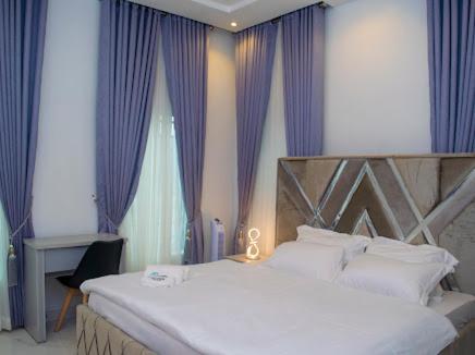 a bedroom with a large bed and purple curtains at The Duch Apartments in Lagos