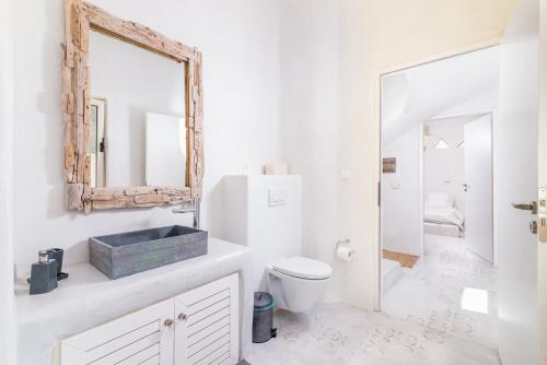 Un baño blanco con inodoro y espejo. en Villa Theona with private pool, en Pitsidia