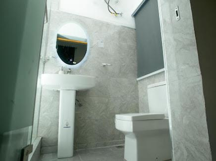 a bathroom with a sink and a toilet and a mirror at The Duch Apartments in Lagos