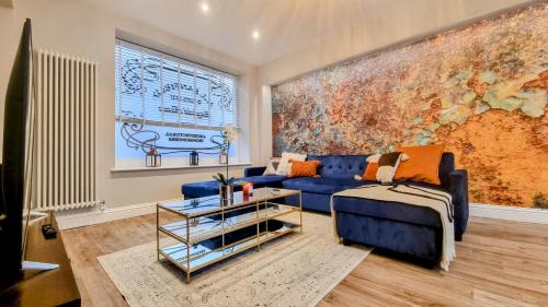 a living room with a blue couch and a large painting at The 4-Bed Brighton Escape in Brighton & Hove