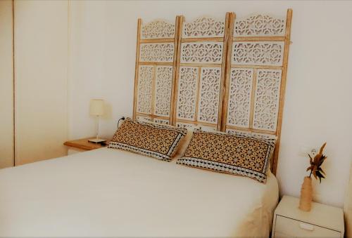 1 dormitorio con cama blanca y cabecero de madera en Apartamento Las Canastas Cádiz Centro, en Cádiz