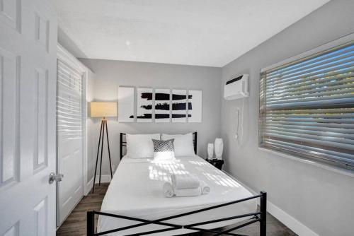 een witte slaapkamer met een bed en een raam bij Rustic Retreats Cozy 1BR For 4 Guests Minutes From Las Olas in Fort Lauderdale