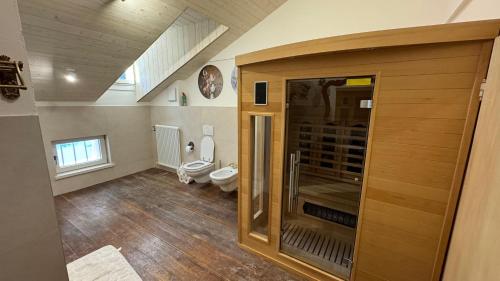 a bathroom with a toilet and a wooden door at Casa Vettori in San Niccolò Comèlico