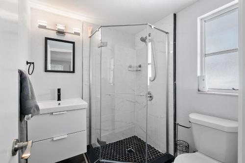 a white bathroom with a shower and a toilet at Ultimate Private Home with Heated Pool in Sarasota
