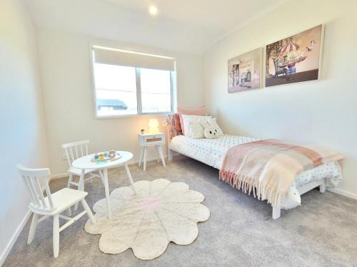 a bedroom with a bed and a table and chairs at Hosts on the Coast - Bright New Delight on Kupe in Whitianga