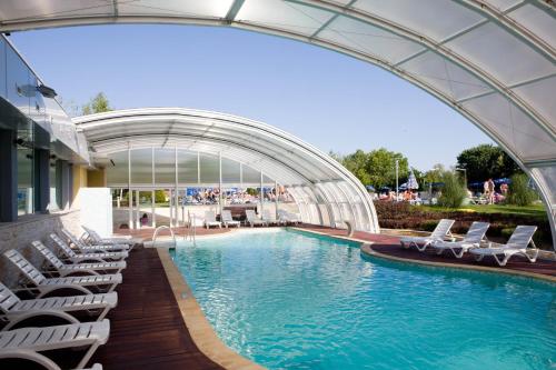 a swimming pool with lounge chairs and a building at Calimera Ralitsa Superior Hotel - Ultra All Inclusive plus Aquapark in Albena