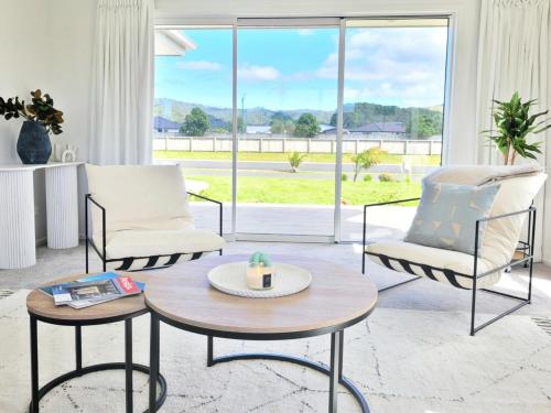 a living room with two chairs and a table at Hosts on the Coast - Bright New Delight on Kupe in Whitianga