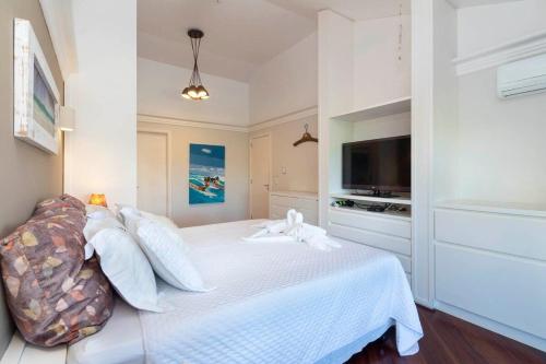 a white bedroom with a bed and a television at 5 quartos piscina e espaço Gourmet (casasmariscal) in Bombinhas