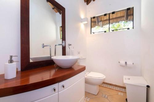 y baño con lavabo, aseo y espejo. en Charmosa Casa Boa Vida Mariscal com piscina., en Bombinhas