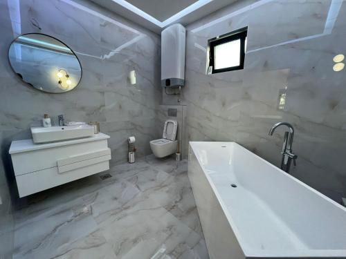 a bathroom with a tub and a sink and a mirror at The Crown Pool Villa in Belgrade