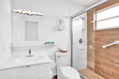 y baño blanco con aseo y ducha. en Waves Beach Town Studio Apartment en Pompano Beach