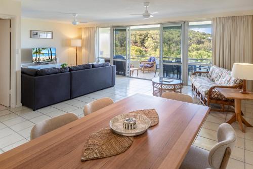 a living room with a table and a couch at Poinciana 109 & Buggy Hamilton Island in Hamilton Island