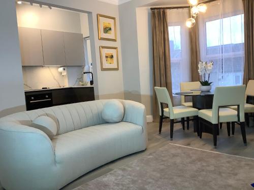 een woonkamer met een bank en een tafel met stoelen bij GREATER LONDON APARTMENT in Londen