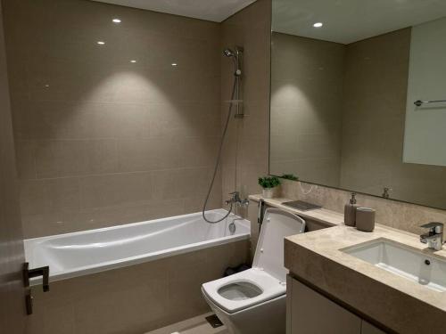 a bathroom with a tub and a toilet and a sink at Burj Khalifa view - Modern 1BDR apartment in Dubai