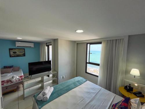 a bedroom with a bed and a tv and a window at Ponta Negra Flats Confort Accommodations Vista para o Mar in Natal