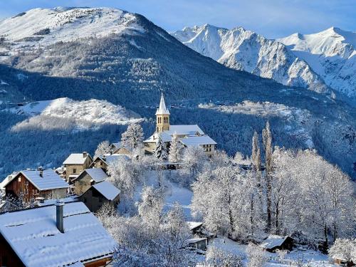 a church in the snow with mountains in the background at Hôtel Chalet Le Panoramique in Mizoën