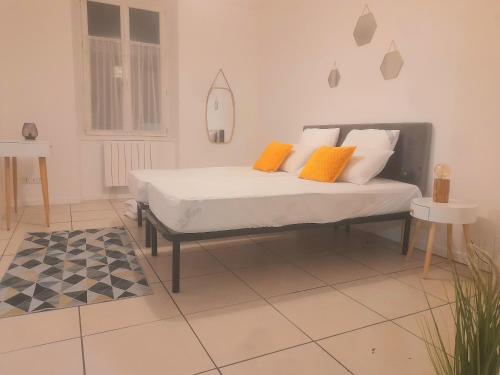 łóżko z pomarańczowymi i białymi poduszkami w pokoju w obiekcie Le Fjørd - Appartement confort, rez-de-chaussée, scandinave, parking gratuit w mieście Bourges