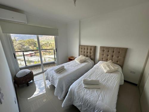 a bedroom with two beds and a large window at Veneto Village Departamento 5min De Carlos Paz- Vista al lago in Villa Parque Siquiman