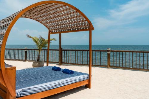 a canopy bed on a beach with the ocean in the background at Hotel Isla del Encanto in Baru